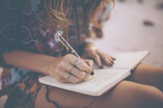 Boho girl writing in her diary wearing a floral dress